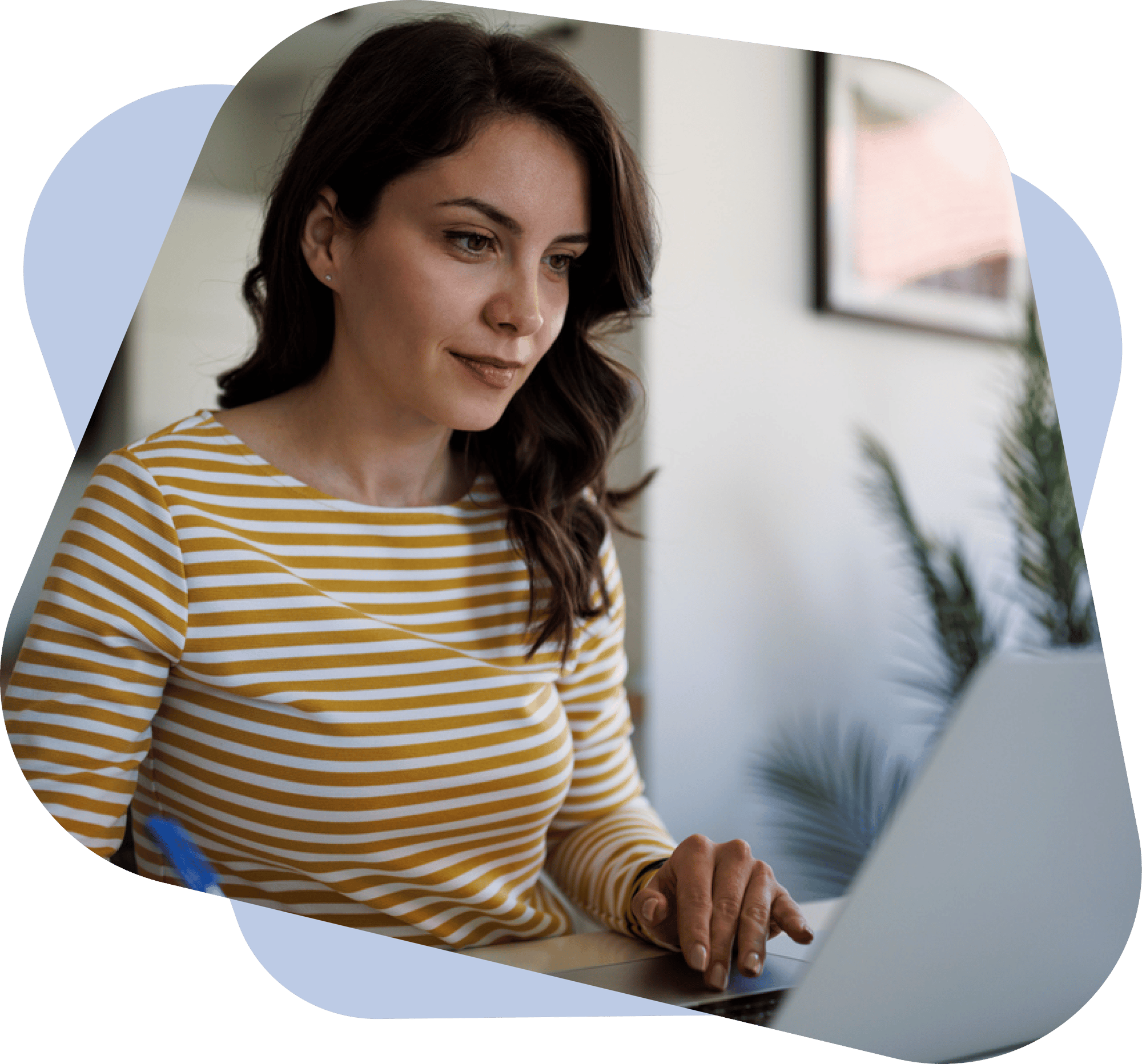 Lady sitting at her laptop smiling. She has long brown hair. She is wearing a dark yellow and white striped long sleeved T-shirt.